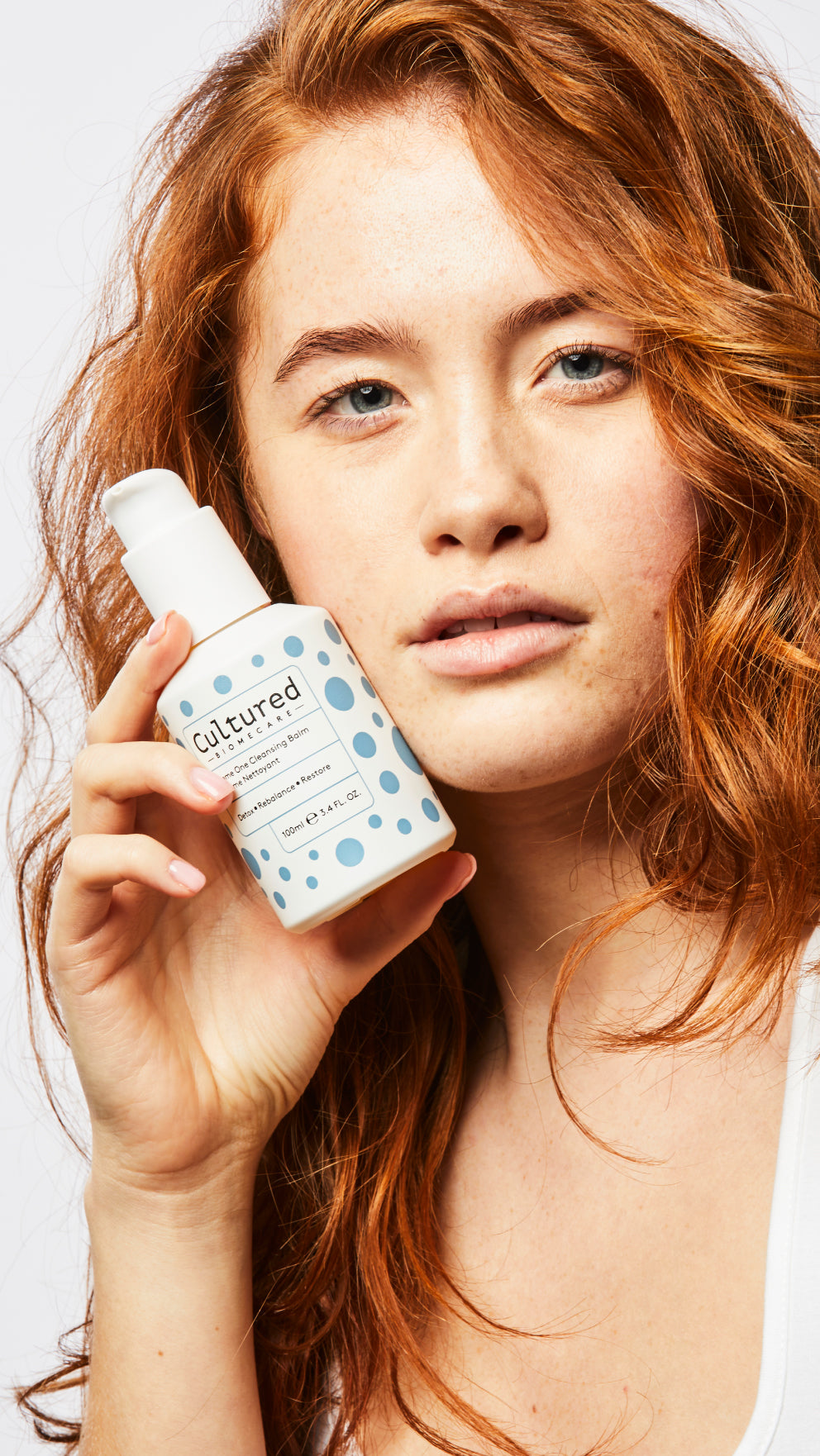 A close-up photo of a model holding the Biome One Cleansing Balm close to her face.