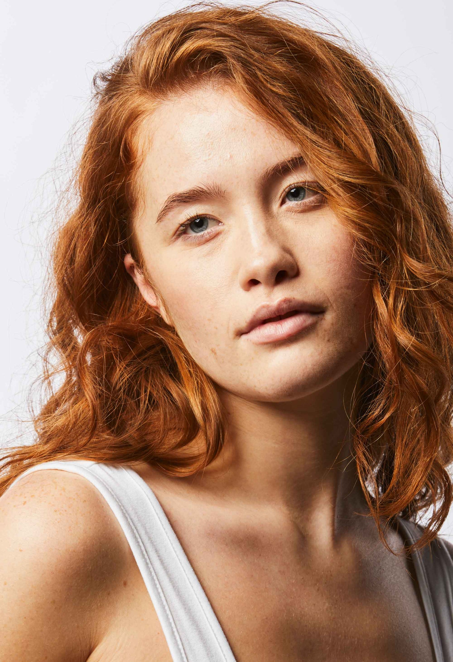 A shoulders up image of a model with clear, glowing skin looking to the side with a shadow across the left side of her face.