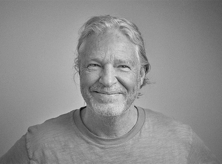 Black and white image from the shoulders up of the founder, Rob Calcraft smiling.