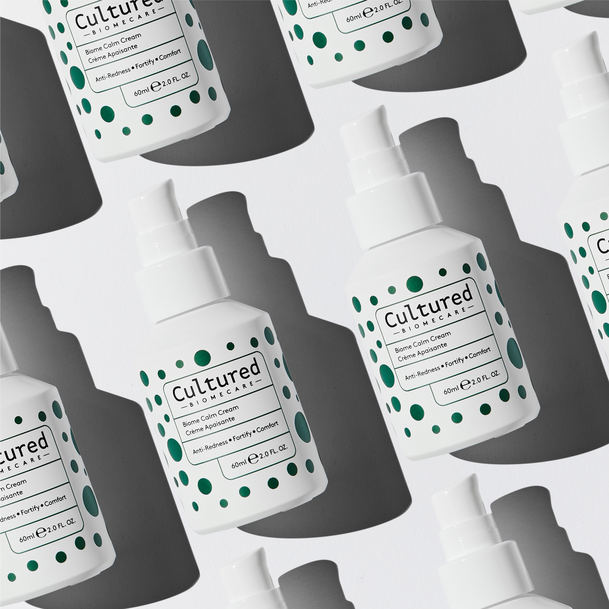 Aerial shot of the Cultured Biomecare Calm Creams lying on their backs in white packaging with dark green spots.
